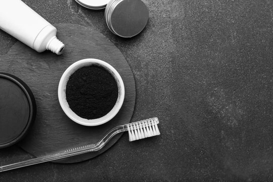 Bowl with activated charcoal tooth powder, tube and toothbrush on dark background