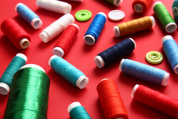 Thread spools with buttons on red background, closeup