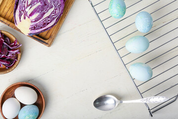 Homemade dyed Easter eggs and purple cabbage on white wooden background