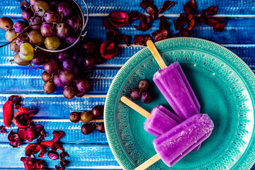 Lollipop style grape ice cream on a stick on a vintage plate on a light blue wooden table. Concept...