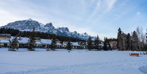 West Canmore Park in winter. Row of lodge and snowcapped Canadian Rockies mountain range. Mount Rundle. Canmore, Alberta, Canada.