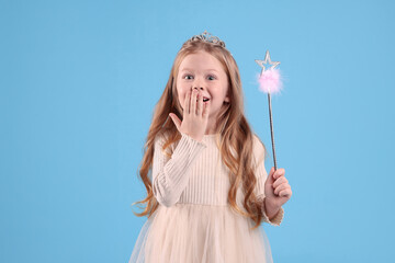 Cute girl in diadem with magic wand on light blue background. Little princess