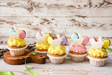 Tasty Easter cupcakes on light wooden table