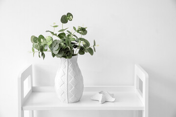 Vase with eucalyptus branches on table