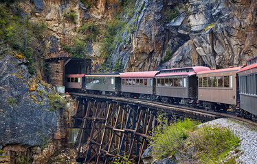 Historic narrow gauge railroad from Skagway, Alaska to White Pass goes from wooden trestle to a wood- lined tunnel entrance