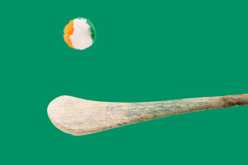 Minimal GAA Irish sport concept. Traditional Ireland gaelic sports stick hurleys with fluffy Irish tricolore balls above it. Green background - obrazy, fototapety, plakaty