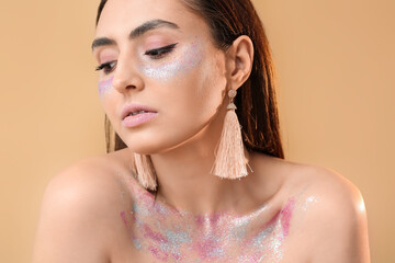 Naklejka premium Young woman with glitter makeup and tassel earrings, beauty and fashion concept, creative cosmetics and skincare
