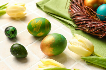 Different Easter eggs and tulips on light tile background