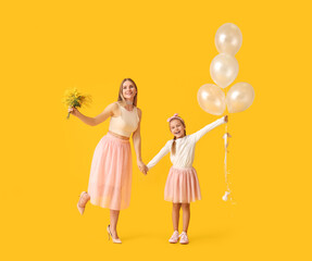 Little girl, her mother with flowers and balloons on yellow background