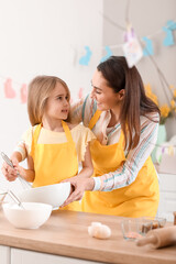 Little girl with her mother preparing dough for Easter cake in kitchen