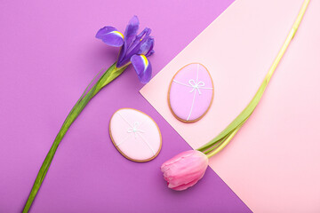 Tasty Easter cookies and flowers on color background