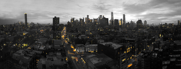 Yellow lights of the New York City skyline shining against a black and white cityscape in Manhattan...