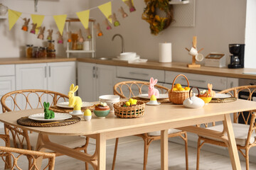Festive table setting with yellow tulips and Easter rabbits in kitchen