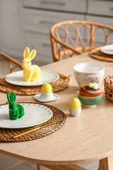 Festive table setting with yellow tulips and Easter rabbits in kitchen, closeup