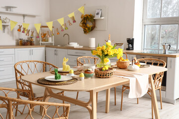 Festive table setting with yellow tulips and Easter rabbits in kitchen
