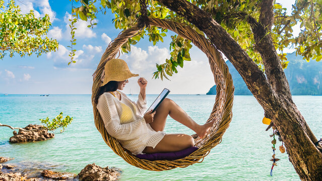 Traveler woman relaxing on straw nests using tablet at Railay beach Krabi, Asia business people on vacation at resort work with computer notebook, Tourist travel Phuket Thailand summer holiday trip
