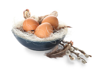 Bowl with Easter eggs, feathers and pussy willow branches on white background © Pixel-Shot