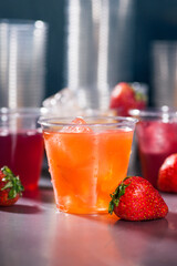 Clear plastic cups with red yellow and orange juice drinks splashing from ice cube on white background