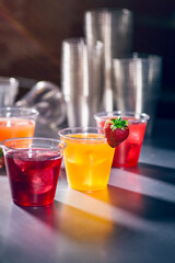 Clear plastic cups with red yellow and orange juice drinks splashing from ice cube on white background