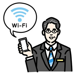 スマートフォンを持ってWi-Fiの説明をしているバッヂのついたスーツを着たメガネをかけた中年男性
