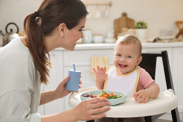 Obraz na płótnie Canvas Mother feeding her cute little baby in kitchen