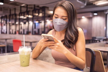 Asian woman sitting separated in restaurant eating food .keep social distance for protect infection from coronavirus covid-19, restaurant and social distancing concept.