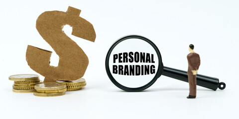 On a white surface, a dollar symbol, a human figure and a magnifying glass with the inscription - PERSONAL BRANDING