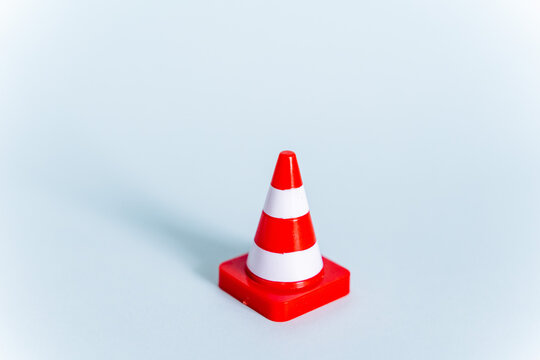 A toy road cone on a minimalist blue background. Road signs in mini-format. Rules of the road. Red signal cone - Powered by Adobe