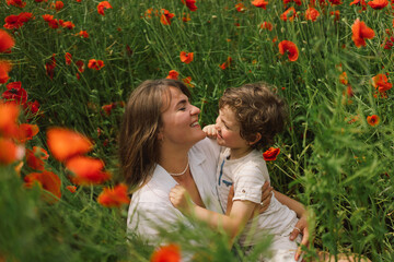 Happy Mother's Day. Little boy and mother is playing in a beautiful field of red poppies. People and nature. Rural scene