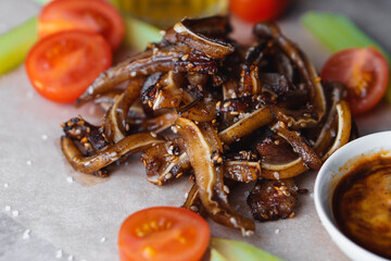Selective focus on fried ear of pork with tomatoes celery and sauce sprinkled with sesame seeds