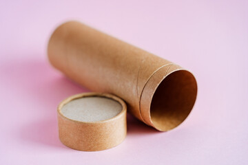 Open cardboard box for pencils. A tube of craft paper on a pink background. Packaging paper