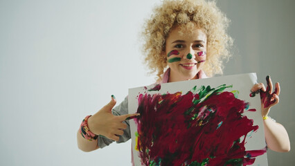 Young proud female artist presenting her artwork - acrylic paint on paper sheet. High quality photo