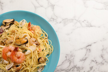 Delicious pasta with sea food on white marble table, top view. Space for text