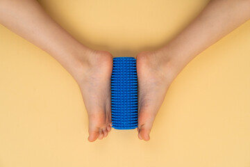 blue needle roller for massage and physiotherapy on a beige background with the image of a child's...
