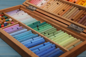 Drawing pastel set in wooden box light blue table, closeup