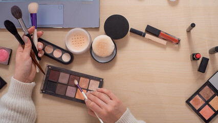 A faceless woman watches online training from a professional makeup artist on a laptop. Distance learning