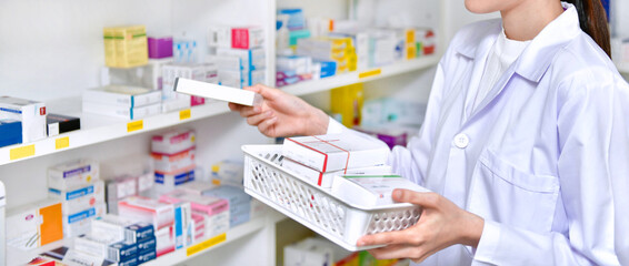 Pharmacist chemist woman standing refills the shelves with new stocks in pharmacy drugstore