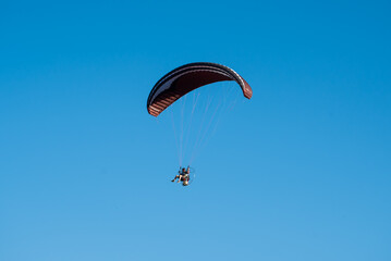 person flying in paragliding, sunny sky in the background