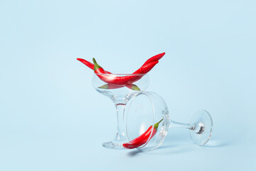 Glasses with hot chili peppers on blue background
