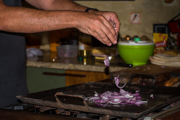 Fototapeta na wymiar man's hands putting chopped onion on a kitchen griddle, background food