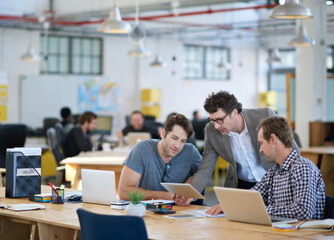 We make technology work for us. Shot of business colleagues discussing matters with the help of wireless technology in their office.