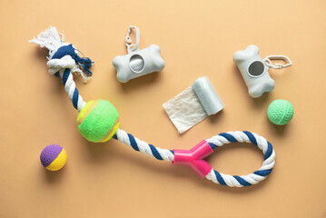 Pet waste bags and toys on color background