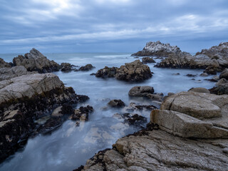 Fototapeta na wymiar A rocky section of coastline near Monterey Bay in California, on an overcast day at sunset, long exposure.