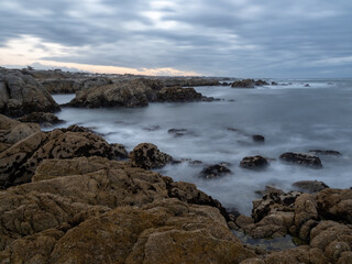 Fototapeta na wymiar A rocky section of coastline near Monterey Bay in California, on an overcast day at sunset, long exposure.