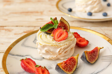 Plate of tasty Pavlova cake with fresh fruits on table