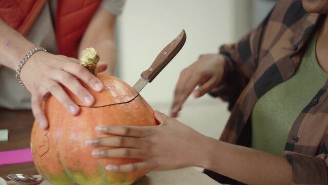 A handsome young lady is carving the pumpkin