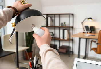 Man changing light bulb in office lamp, closeup