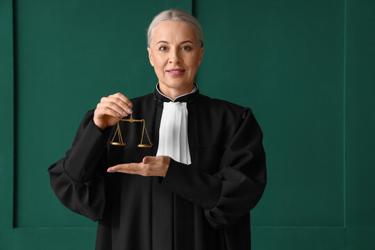 Mature female judge with justice scales on green background