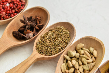 Wooden spoons with different spices on light background, closeup