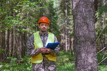 Naklejka na ściany i meble Forest engineer stands in the forest in working clothes.